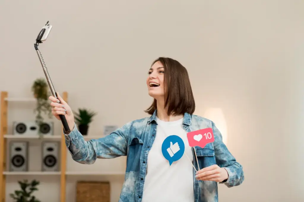 A female content creator smiling while taking a selfie with a phone on a stick, symbolizing the differences between KOC and KOL in influencer marketing.