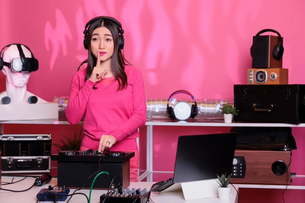 Seorang perempuan sedang menggunakan headphone untuk mendengarkan musik dengan latar belakang warna pink, mewakili elemen kreatif dalam strategi social media marketing.